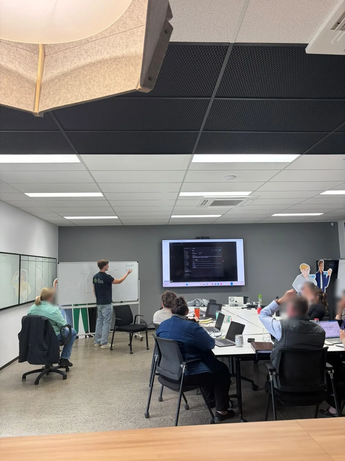 Adam leading a client workshop at a whiteboard, attendee faces blurred